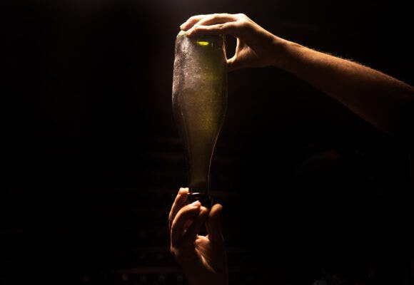 Man checking sparkling wine in bottle on light