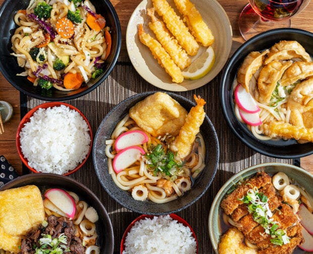 Japanese food sitting next to a glass of wine