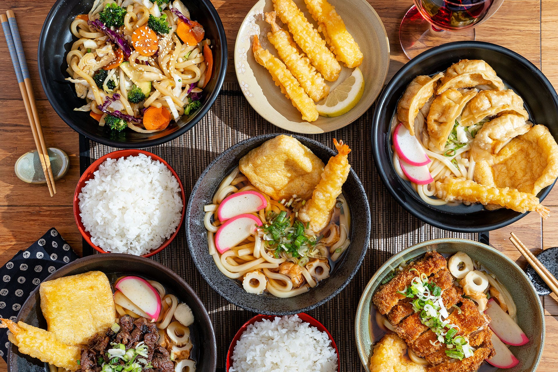 Japanese food sitting next to a glass of wine