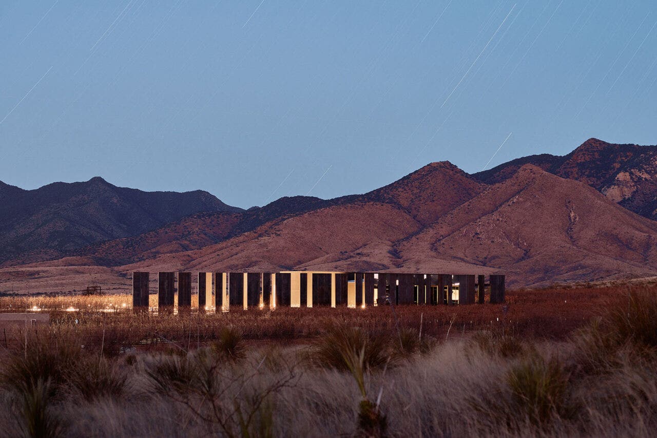 Los Milics Vineyard tasting room buiding in middle of desert, lit up at night