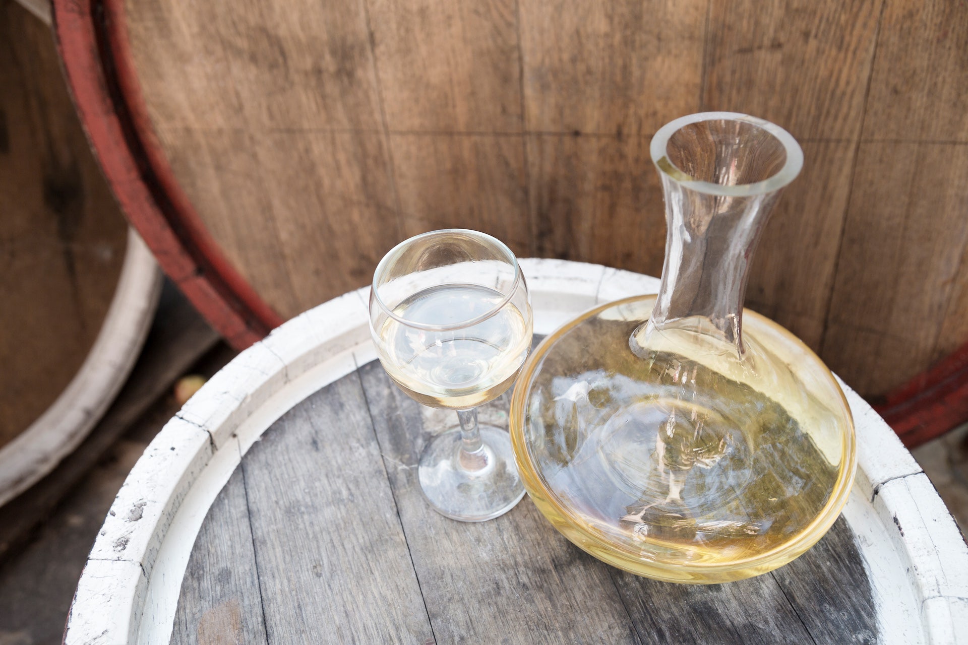 Decanted white wine and wine in a glass atop a barrel