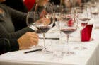 White table-clothed table with many glasses of wine on top