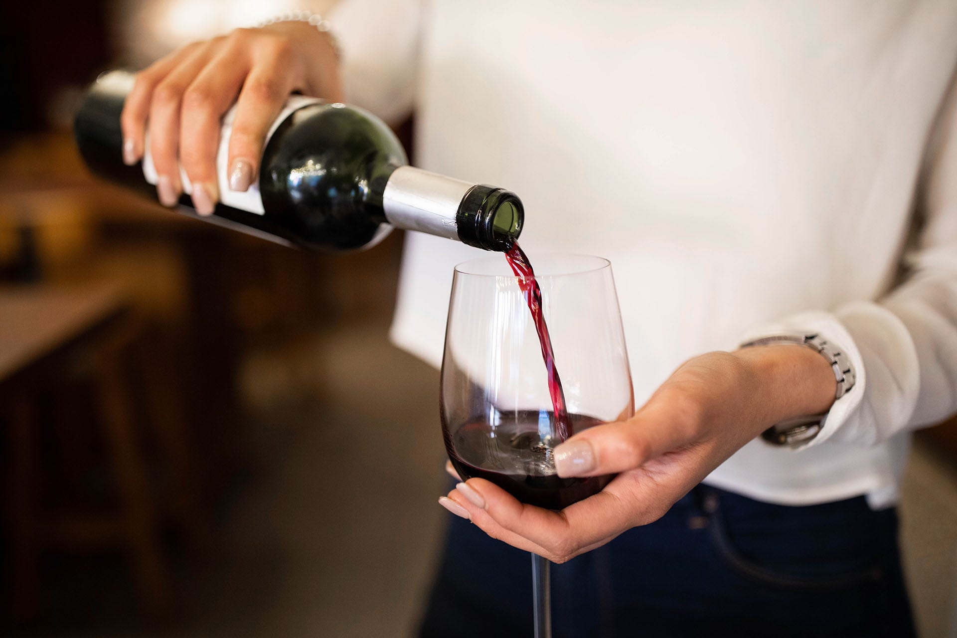 Close-up of a woman hand pouring wine into a glass