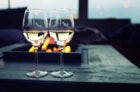 Two glasses of wine by a fire